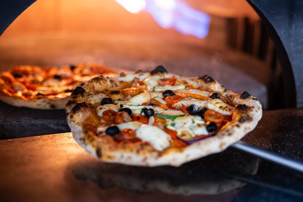 Handmade traditional Neapolitan wood fired pizza being cooked in a clay pizza oven