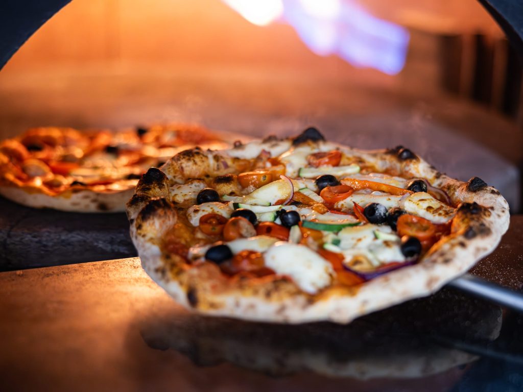 Handmade traditional Neapolitan wood fired pizza being cooked in a clay pizza oven
